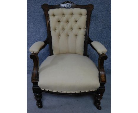 A late Victorian carved walnut armchair on turned tapering supports terminating in ceramic casters. H.97cm 