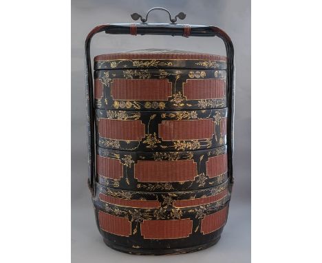 An oriental black lacquer four section lidded storage container, of cylinder form, swing handle, simulated rattan panels, hei