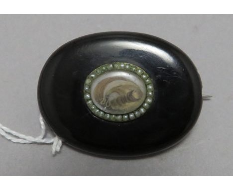 A late Georgian, early Victorian oval Whitby jet memorial brooch with seed pearl and plaited hair. 4 cm long.  (1)Condition: 