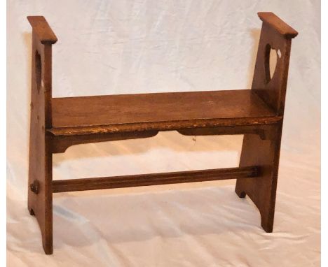 An Arts & Crafts oak open bench seat, two pierced hearts, above a solid moulded edge seat, raised upon shaped supports united