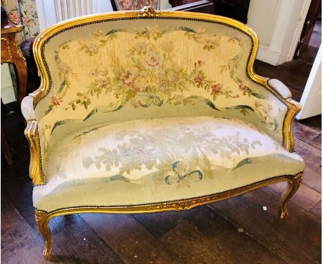 A Louis XV revival giltwood two seater sofa, centre top foliage carving on a spoon back with scrolling arm supports, on a ser