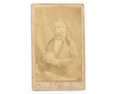 Dickens, Charles. Photographic portrait of Dickens holding a book at his desk, by Herbert Watkins, [c.1858], albumen print, s