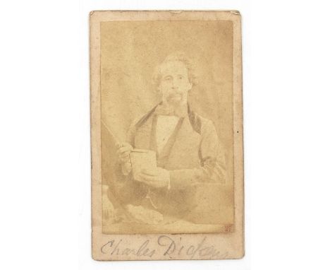 Dickens, Charles. Photographic portrait of Dickens holding a book at his desk, by Herbert Watkins, [c.1858], albumen print, s