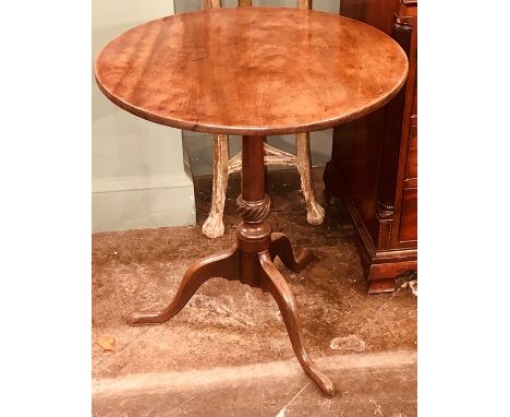 A George III mahogany tilt top table, circa 1820, circular top above a turned column, on a tripod form base, raised on three 