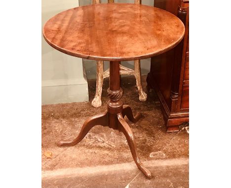 A George III mahogany tilt top table, circa 1820, circular top above a turned column, on a tripod form base, raised on three 