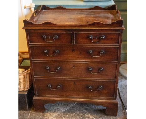 A George III mahogany bedside commode, circa 1800, in form of a chest of drawers, full carved gallery top with moulded edge, 