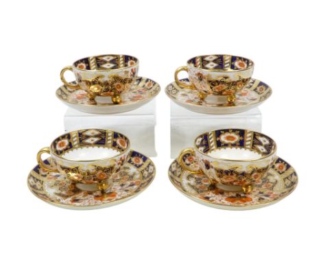 A set of four Royal Crown Derby tea cups and saucers - Imari decorated, the cups raised on gilt ball feet.