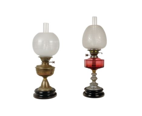 A late 19th century oil lamp - with ruby glass reservoir and fluted baluster support and circular base, together with another