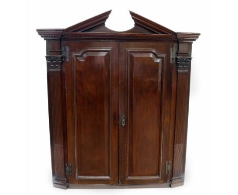 George III mahogany two door corner cupboard, architectural pediment with key cut moulded decoration, two raised and fielded 
