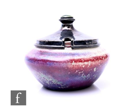 A Ruskin Pottery High Fired jar, of compressed ovoid form, purple over sang de boeuf glaze, the associated planished silver c