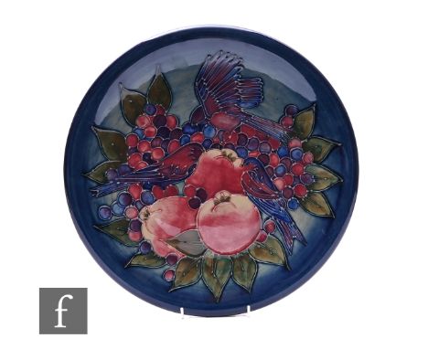 Sally Tuffin for Moorcroft Pottery, a Finches charger, tubeline decorated with perched birds amongst apples and grapes over g