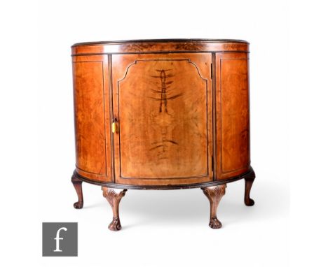 A 1930s Queen Anne style mahogany demi-lune side cabinet enclosed by a beaded panel door on shell carved cabriole legs and sc