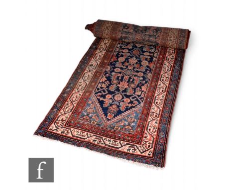 An early 20th Century Kashan woollen runner, the rug with a central oatmeal coloured medallion upon a blue field, all within 