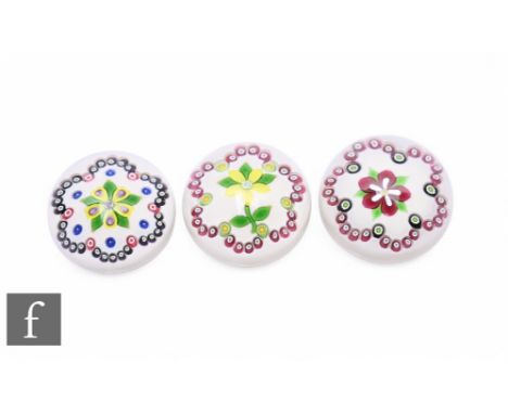 A group of contemporary William Manson glass paperweights, each having a central lamp work stylised flower, the first with ye