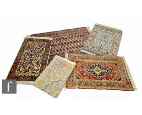 Four late 20th Century woollen rugs manufactured in Pakistan, to include a rug with a blue central medallion upon a maroon fi