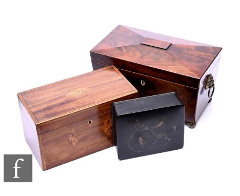 A Regency mahogany tea caddy, of sarcophagus form with brass lion's mask handles, on ball feet, fitted twin lidded compartmen