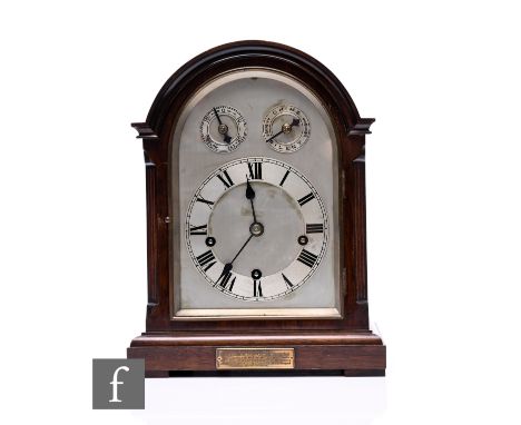 An Edwardian mahogany mantle clock in domed case, the arch silvered dial incorporating slow/fast and chime/silent subsidiary 