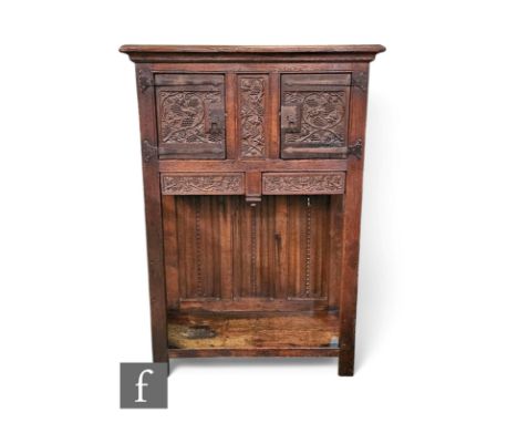 An 18th Century and later carved and constructed floorstanding cabinet, enclosed by a pair of doors decorated with vines and 