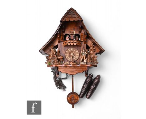 A 20th Century Black Forest cuckoo clock, weight driven operation causing the doors to open and dancing figures to revolve un