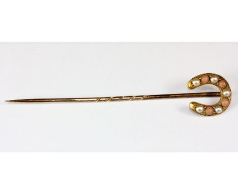 A yellow metal (tested min 9ct gold) horseshoe stick pin set with coral and seed pearls.