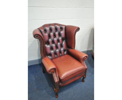 A RED LEATHER BUTTON BACK WINGED ARMCHAIR with cabriole front legs (condition:- some fading to seat and arms, no rips or tear