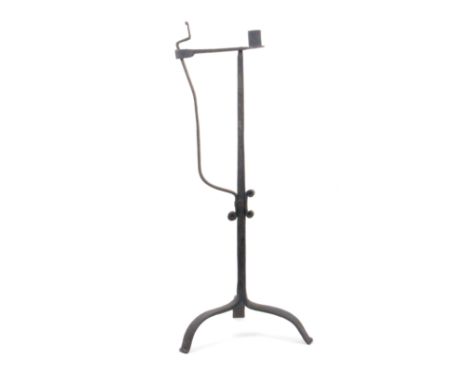An 18th Century wrought iron candle and rush light holder, on tripod base, scroll detailing to stem, 63cm
