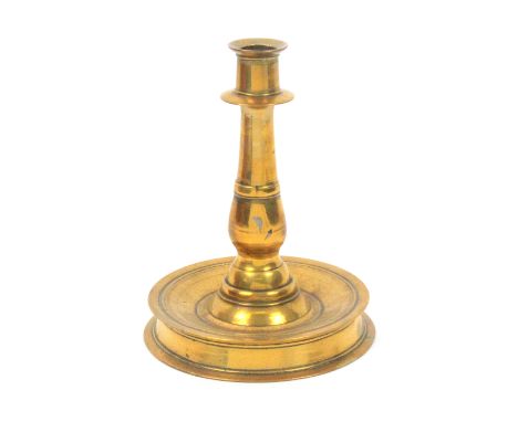 A 17th Century brass candlestick, on circular base tapering downward to the stem, 20cm high, 15cm dia. at base               
