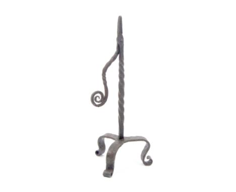 A 17th Century wrought iron rush nip, spiral twist stem with scrolling terminal to arm, on tripod base with scroll feet, 30cm
