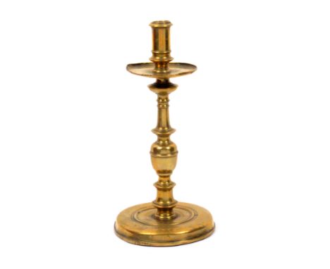 A 17th Century brass candlestick, domed circular base to a turned stem with broad drip pan, 25cm high, 12.5cm dia. at base   
