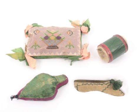 Four pin cushions comprising a green leather drum form example, 3cm, another as a set of bellows in green velvet, 8cm, a rect