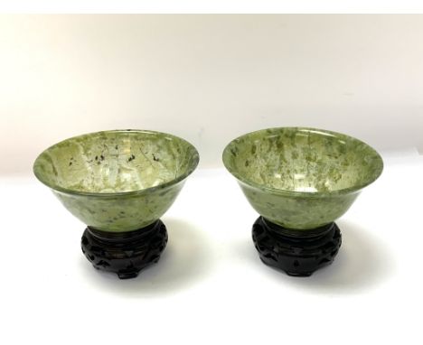 A pair of turned spinach jade bowls with 2 small carved wooden stands. (10cm diameter x 4.5cm).