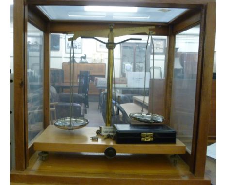 A set of mid 20thC chemical balance scales, in a mahogany finished, glazed cased  bears a label W & J George & Becker Ltd, on