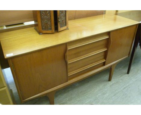 A 1960s teak finished sideboard, the three central drawers flanked by a pair of doors with grab handles, raised on tapered fe