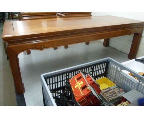 A modern Chinese light coloured hardwood coffee table, having a panelled top, over a scrolled apron, raised on moulded, squar