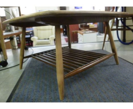 An Ercol beech and elm coffee table, the top having rounded corners, over a spindled undershelf, raised on turned, tapered le