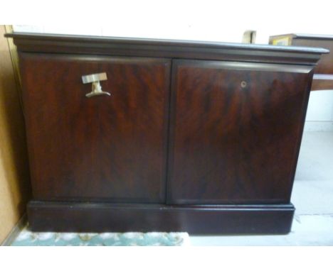 A stag mahogany finished cupboard, having a shelf top, over a pair of doors, on a plinth  26''h  37''w        BSR