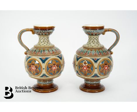 Pair of Mettlach German ewers, decorated in relief with floral medallions, approx 18 cms h, impressed marks to base.&nbsp;