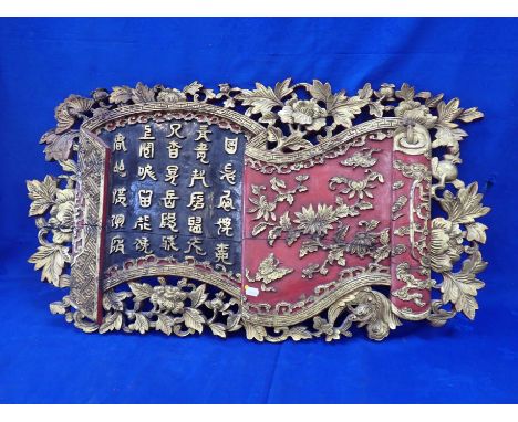 A CHINESE CARVED AND LAQUERED PANEL in the form of a scroll with paeonies and butterflies, bearing a carved text 50 x 88cm