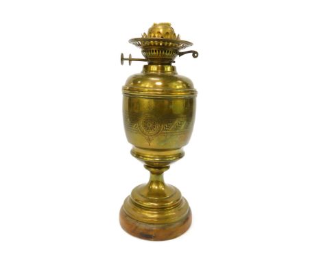 An early 20thC duplex brass oil lamp, with engraved decoration, raised on a wooden base, no chimney or shade, 58cm high.