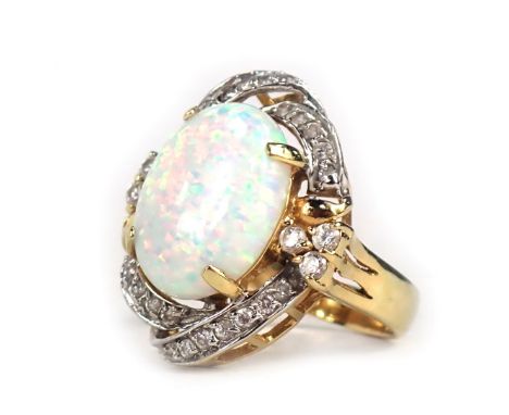 A dress ring, with oval imitation opal, in four claw setting, surrounded by swirl of diamonds, in yellow metal frame stamped 