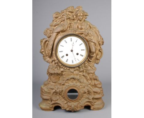 A cast and gilt metal clock with a maiden and peacock design, stamped N Muller to front with enamel dial having roman numeral