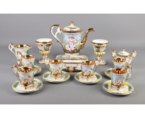 A Capodimonte tea service featuring gilt edging and decorated with cherubs. Comprising of cups, saucers, teapot, trinket box,