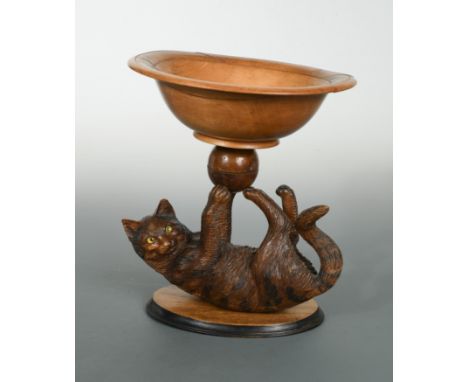 the reclining feline supporting a turned wood bowl on three paws, mounted to an oval base 28cm highCondition report: Some lig