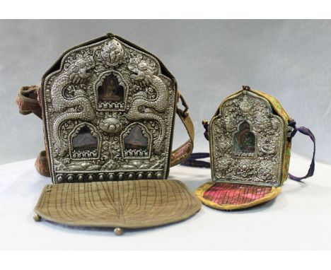 of arched form, the white metal 'mask' embossed with two dragons around three small ceramic Buddha figures in glazed recesses