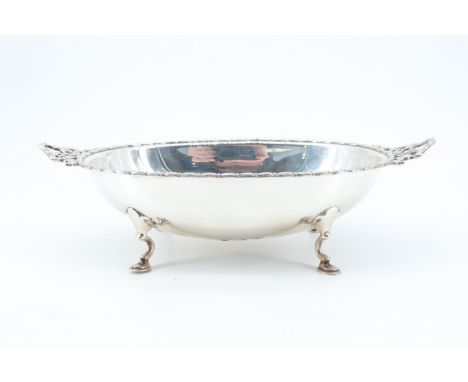 A George III influenced oval silver bowl, having Neoclassical edge moulding and horizontal pierced ribbon lug handles, raised