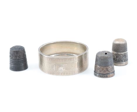 An engine turned silver napkin ring with a vacant cartouche, Birmingham, 1940, together with three silver thimbles, 22 g gros