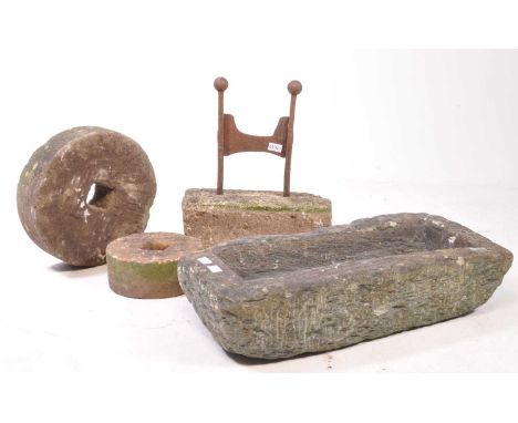 A collection of four pieces of stone gardenalia. The collection to include two wheels, a trough and boot scraper with cast ir