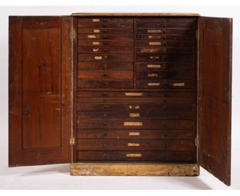 An overpainted pine tool/collectors cabinet: the double panel doors enclosing an array of 28 short and long graduated drawers