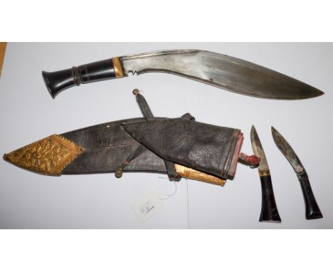 A Malayan Kukri: with 34cm single edged blade, horn grip, with two smaller knives contained in a leather and gilt brass mount