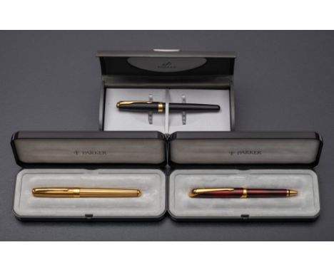 Two Parker Sonnet Dimonite roller ball pens: one in a red lacquer finish, the other in gold with green stripes, together with